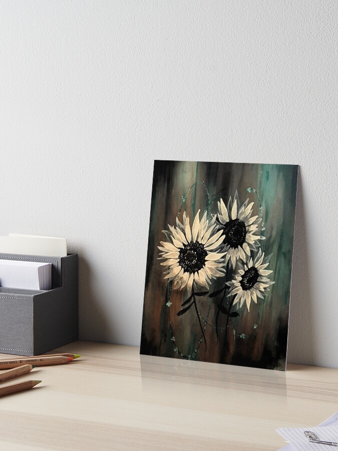 Mixed-media painting of three stylized sunflowers with large dark centers and pale petals against a dark, moody background with subtle green and brown textures